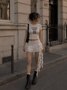 Woman in a crop top and ruffled skirt with headphones on a street