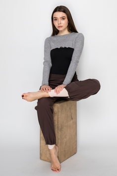 Woman with long brown hair sitting on a wooden box in a studio
