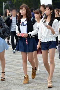 Two young women walking on a street with other people in the background
