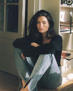 Woman with long dark hair sitting on the floor in natural light