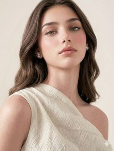 Woman with long wavy hair and earrings wearing an off-shoulder top