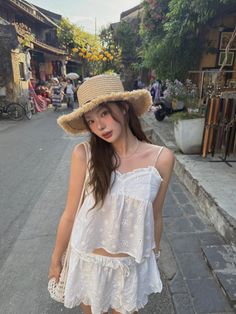 Woman in a straw hat and white outfit on a street