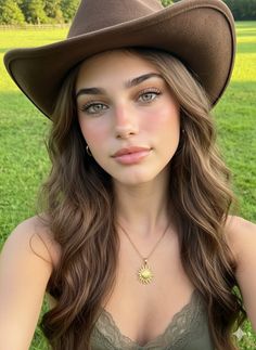 Woman with long hair and a cowboy hat in a green field