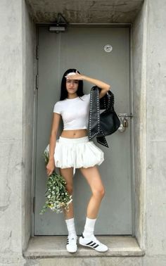 Woman in a white crop top and bubble skirt holding flowers