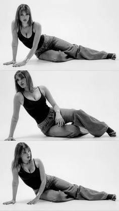 Woman in a black tank top and jeans posing on the floor in a studio
