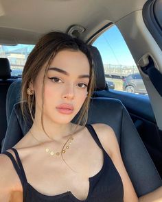 Woman with long hair and a black top sitting in a car