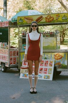 Woman in a red dress and sunglasses standing in front of a food cart