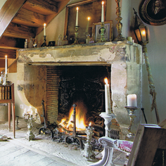 Rustic fireplace with lit candles and antique decor