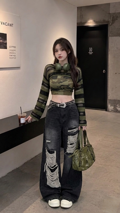 Woman in a camouflage crop top and ripped jeans with headphones around her neck