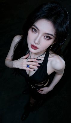 Woman with long black hair and dark lipstick in a black top with dramatic lighting