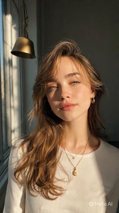 Woman with long hair and jewelry in soft golden hour lighting indoors