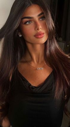 Woman with long dark hair wearing a black top and jewelry