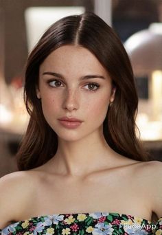 Woman with long brown hair and freckles wearing a floral off-the-shoulder top