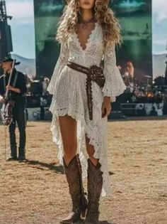 Woman in a white lace dress and cowboy boots at an outdoor music festival