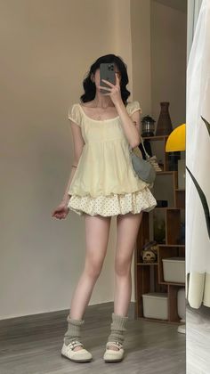 Woman in a yellow top and polka dot skirt taking a mirror selfie