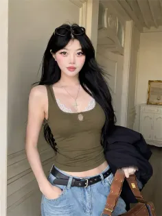 Woman with long black hair wearing a tank top and jeans indoors
