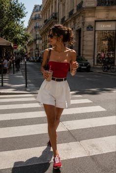 Woman in a red tube top and white shorts crossing a street on a sunny day