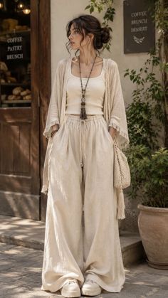 Woman in wide leg pants and a cardigan standing outdoors