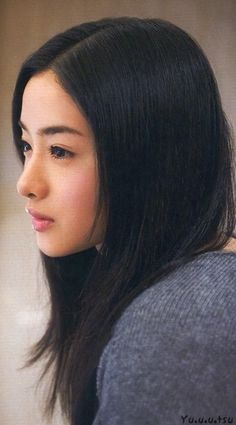 Woman with long black hair in a grey sweater, captured in a soft-lit side profile
