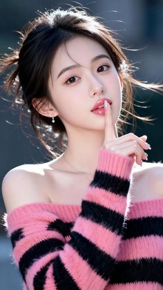 Woman in a pink and black striped off-shoulder sweater with a finger to her lips