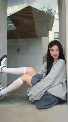 Woman with long dark hair wearing a grey jacket and white knee socks, sitting outdoors