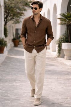 Man in a brown linen shirt and light pants walking outdoors