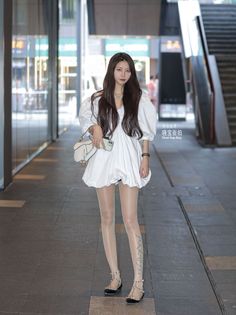 Woman in a white puffy dress and sheer stockings on a city street