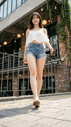 Woman in a white crop top and denim shorts walking on a street