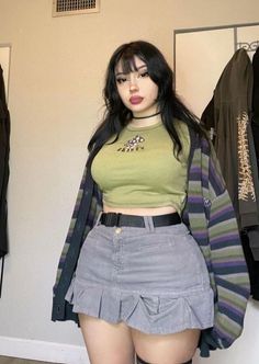 Woman with long black hair and bangs wearing a cropped top and mini skirt indoors