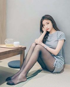 Woman in a gray dress and black pantyhose sitting on the floor indoors