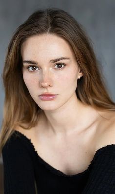 Woman with long brown hair and freckles wearing an off-shoulder top
