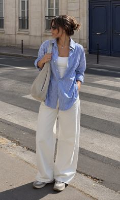 Woman in a striped shirt and white wide-leg pants standing on a street