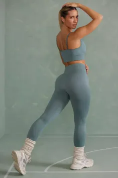 Woman in blue athletic wear and sneakers posing indoors