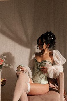 Woman in a corset and thigh-high stockings holding a perfume bottle