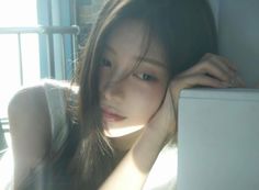 Woman with long hair resting her head on her hand in soft natural light
