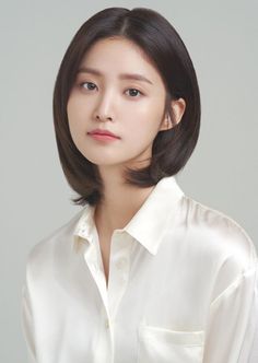 Woman with short dark hair wearing a white collared shirt in a studio setting