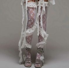 Person wearing white lace leggings with ruffles and sparkling sandals