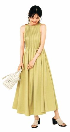 Woman in a light green pleated midi dress holding a braided bag