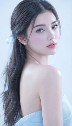 Woman with long dark hair and a blue ribbon, looking over her shoulder