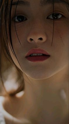 Close up of a woman's face with wet dark hair and red lipstick
