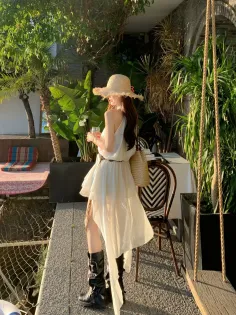 Woman in a white dress and straw hat outdoors during golden hour