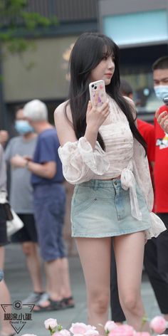 Woman with long black hair wearing a white blouse and denim mini skirt on a street
