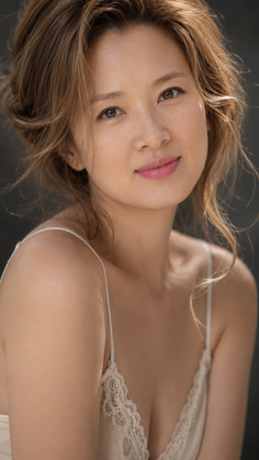 Woman with long hair wearing a lace top, looking at the camera