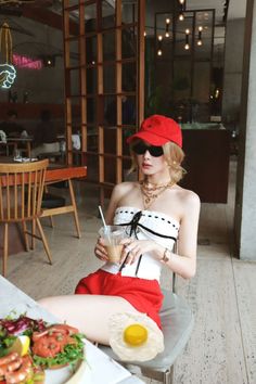 Woman in a red cap and strapless top sitting at a cafe table