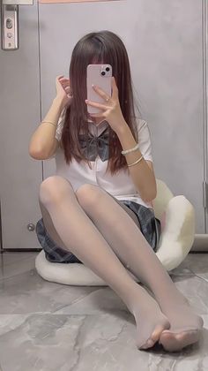 Person in a school uniform and white tights taking a mirror selfie