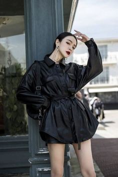 Woman in a black leather jacket and dark lipstick posing outdoors