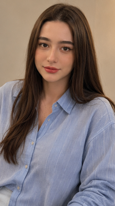 Woman with long brown hair wearing a blue collared shirt indoors