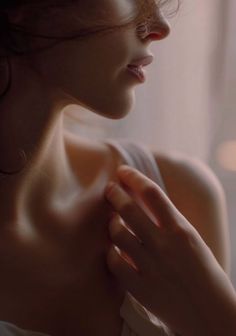Close up of a woman's upper body with soft lighting and a delicate pose