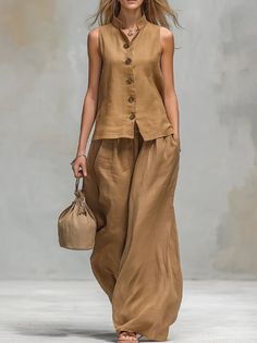 Woman in a brown linen sleeveless top and wide leg pants holding a small bag