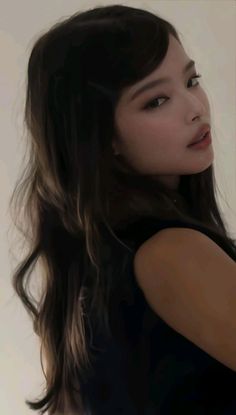 Woman with long black hair wearing a black top, looking over her shoulder